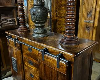 Set of Large Wood Candle Holders and Temple Vase Sitting atop an Antique Sideboard with Rolling Doors from Jupiter Iron Works Est. 1925