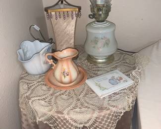 Round table with glass top and table linens, lamps, small pitcher and bowl