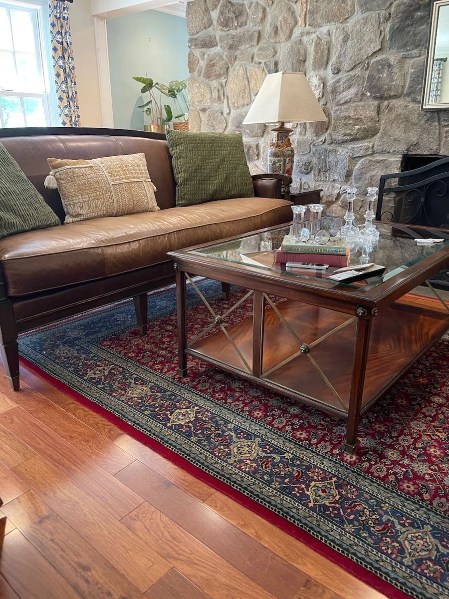 Vintage distressed leather sofa, oriental rug, coffee table, Tiffany dolphin candle holders, fireplace screen and tools