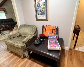 A plush overstuffed visiting chair in a lovely light green velour . And a Large leather? ottoman. 3 nice pairs of binoculars, a vintage pinball game and a very nice folding game seat Hook ‘em!