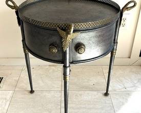  Trouvailles French Empire Metal Drum Tray Table is accented with beautiful brass details and decorative bird mounts. Features a lift off top and dual cabinet doors. 

Measures 23 inches tall and 25 inches in diameter. 