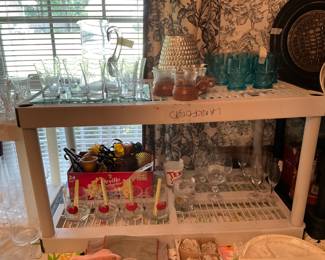 Left to right - top - set of cut glass pitcher, glasses & mirror holder, wood & glass cup holders, large bee hive container; bottom shelf in back in box - votive candle holders with metal, drink glasses - 4- in front, miscellaneous glasses to right