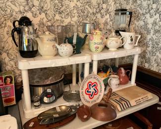Trays, including an America Revolution Bicentennial one, crock,pot, metal & carved wood containers teapots, vintage coffee maker pots with cords & insides, blender, & Dewar’s pitcher