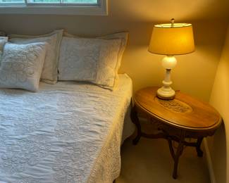 King bed, oval antique side table. and porcelain and milk-glass lamp