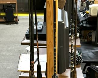 Vintage fishing poles and in the background are a large amount of TVs, monitors, and electronics.