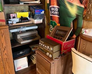 A small mish-mash of items are shown here, but the life-sized Bud Light cutout does catch one's attention. Notice the electric typewriter on the shelf, the vintage radio parts, and the black Polaroid case.
