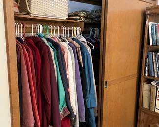 In this closet hang a number of clothing items: shirts, jackets, and more.