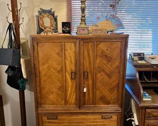 The same roll-top desk is off to the right of the armoire-style entertainment center, which itself is right of the coatrack.