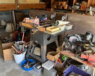 It looks like a small table saw or router. It's hard to tell from the items on top. There is a motorized grinder, multiple hammers, an air compressor (in the back), and a couple of circular saws.