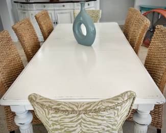 White painted dining table with - can sit 8-10 people with leaf in it. Six sisal/rattan chairs and two upholstered green chairs.