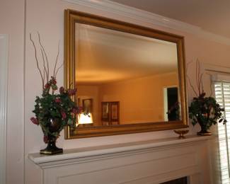 Gilt framed, beveled mirror over fireplace in den