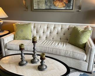 Curved single-cushion couch, 100% wool area rug, black wood and ivory fossil stone cocktail table, floral canvas framed, candle scones, pillows and pillar candle holders