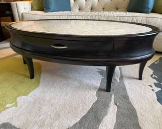 Another view of the oval cocktail table with black wood and ivory fossil stone top
