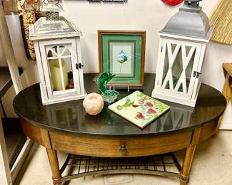 Close-up of oval coffee table, misc. decor and wall art