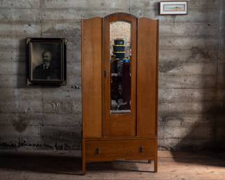 An Art Deco Oak Armoire, early 20th century. This armoire has a top clothing rod with four permanently attached hooks and a large bottom drawer. The top section detaches from the base for easy moving. The handle for the armoire door has broken off, but is included for future restoration.