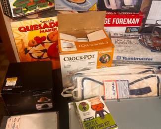 This is a table FILLED with excellent little measures for the home! The left side of the table is filled with small kitchen appliances interior original boxes, and the right side is filled with loads of medical, health & beauty and more! 