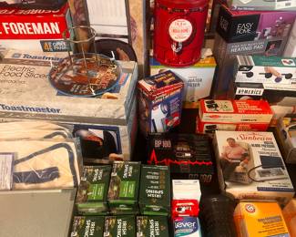 This is a table FILLED with excellent little measures for the home! The left side of the table is filled with small kitchen appliances interior original boxes, and the right side is filled with loads of medical, health & beauty and more! 