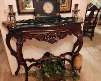 Marble top carved entry table, antique clock, floral arrangement