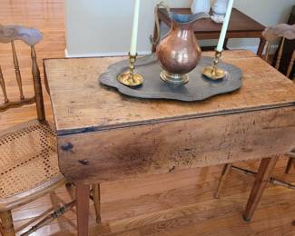 Rustic double-drop leaf table showing years of wear, pair of cane seat tole chairs