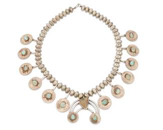 229
A Southwest Coin Silver Squash Blossom Necklace
Early/mid-20th century
Appears unmarked
The Mercury head single strand bead necklace accented with twelve "Walking Liberty" silver dollars each with set turquoise, suspending a naja with a central oblong turquoise stone and two 1920s quarters (1925 and 1929) at the terminals
26" L x 2.5" H
520.1 grams gross
Estimate: $600 - $900