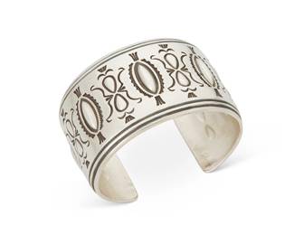 252
A Fidel Bahe Navajo Sterling Silver Cuff Bracelet
Fidel Bahe (b. 1949, Diné)
Late 20th/21st century
Etched: BAHE [stylized]; further faintly stamped: Sterling
A wide silver cuff bracelet with repoussé and stamped motifs
7" total inner C x 1.625" H, with a 1.125" gap
93.5 grams
Estimate: $400 - $600