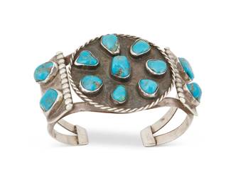 256
A Southwest Silver And Turquoise Cuff Bracelet
Early/mid-20th century
Appears unmarked
A two-wire cuff with chunky nugget turquoise cluster-set to a round central panel and shoulders
6.75" total inner C x 1.75" H, with a 1" gap
68.6 grams gross
Estimate: $300 - $500