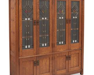 65
A Volpiani Workshop Arts & Crafts Prairie-Style Bookcase
Late 20th century
Burn marked to upper right proper cabinet interior: Volpiani Workshop
The quarter sawn wood bookcase with butterfly and mortis and tenon construction, featuring four custom Paul Crist (b. 1944) leaded glass cabinet doors with white and iridescent glass accents, each revealing two adjustable shelves, above four lower cabinet doors with copper pulls on hammered escutcheons, each revealing a single adjustable shelf
68.25" H x 66.25" W x 17" D
Estimate: $1,000 - $1,500