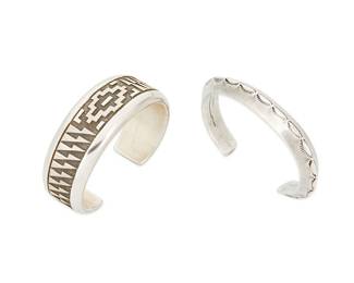 271
Two Navajo Sterling Silver Cuff Bracelets
Two works:

Dan Jackson (1944-2022, Diné)
Late 20th/21st century
Stamped: DA Jackson [within hogan]
A sterling silver cuff bracelet with cast raised textile motif
6.125" total inner C x 0.875" H, with a 1" gap

A Navajo sterling silver cuff bracelet
Early/mid-20th century, Diné
Appears unmarked
A narrow heavy gauge triangular wire cuff with stamped motifs
6.125" total inner C x 0.375" H, with a 1.125" gap

2 pieces
117.1 grams
Estimate: $600 - $900