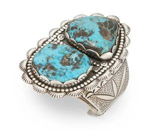261
A Lloyd Oliver Navajo Sterling Silver And Turquoise Cuff Bracelet
Lloyd Oliver (1923-2011, Diné)
Mid/late 20th century
Stamped: LO
A chunky four-wire cuff with a large central plaque with bezel set turquoise slabs and stamped edging and shoulders
7" total inner C x 4" H, with a 1.375" gap
229.4 grams gross
Estimate: $700 - $900