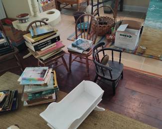 Numerous books, children's chairs, and a tall white painted plant stand grouped looking into the sun porch 