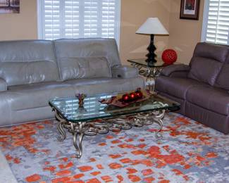 Plush leather couch and loveseat with elegant glass top coffee table.
