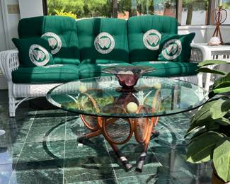3 seat sofa and a glass top coffee table with crossed tennis rackets base