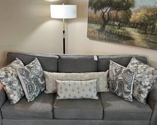 Gray Upholstered Sofa, pillows, floor lamp, art