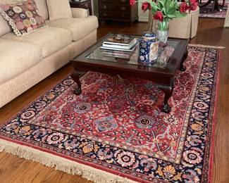 Cream couch, coffee table, beautiful traditional rug.