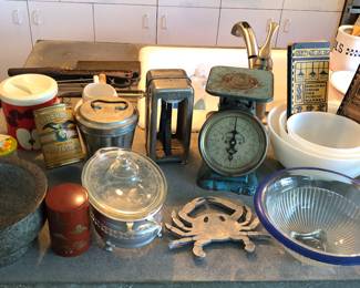 Vintage & newer kitchen items: giant granite mortar & pestle, tins, etched Pyrex casserole w/ caddy, fiber napkin dispenser, old scale, Pike Place Market cookbooks, glass funnels 