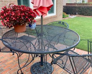 Patio table with four round back chairs and umbrella stand.