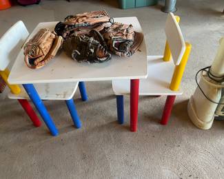kids table with 2 chairs and 4 baseball gloves