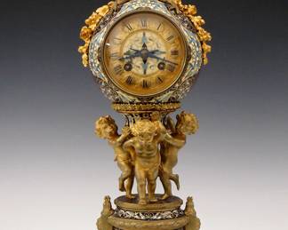 A late 19th century French desk clock by Japy Freres, Paris for Tiffany & CO, New York.  8-day time olny movement with platform escapement multi color cloisonne dial with gilded Bronze chapter ring and Roman numerals, serial #9335.  Finely cast Bronze case with multi color cloisonne top, collars and base, gilded Dove finial with ribbons and swags, supported by three gilded putti on paw feet with a shaped marble plinth.  Original two tone patina with minor wear, running momentarily when cataloged.  15 1/2" high.  ESTIMATE $1,500-2,500