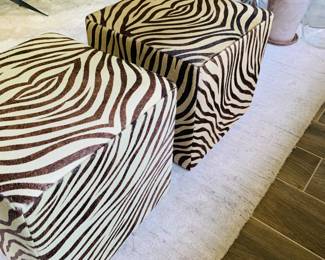 Cowhide rolling ottomans in “Zebra” patterns by Edelman. 
