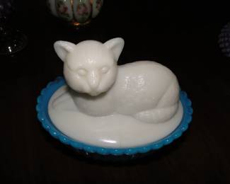 Milk glass cat on blue glass bed, separate's into two pieces.  This is a Westmoreland piece.