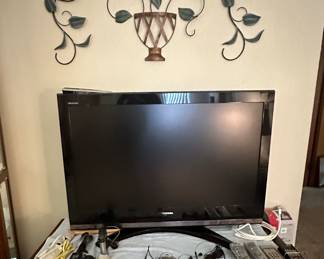 Toshiba Flat Screen TV; TV Stand; Remotes; Wall Decor