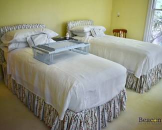 Pair of twin beds with upholstered headboards and matching dust ruffles