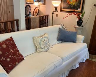 White slip covered sofa, pillows, art