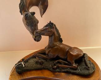 Bronze horses on wooden platform titled "Tender Touch"