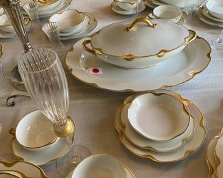 A partial view of the table full of fine china and stemware.