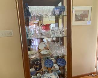 Contemporary lighted china/display cabinet full of glassware and china.