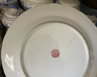 Backside of blue and white ceramic plate with orange, pink floral design and gold details 