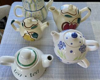Shiny white ceramic painted tea pots, two including their own decorative cup 