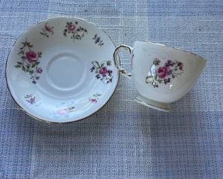 Small white, floral saucer and cup with gold details, separated 