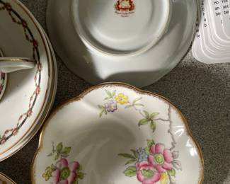 Bottom side of pink, yellow, purple floral ceramic plates with gold detail 